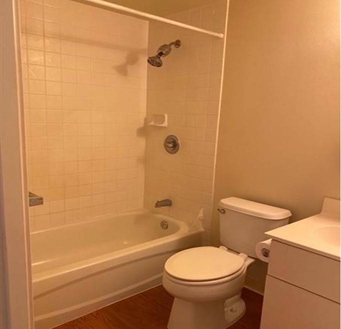 A white toilet sits next to a bathtub in a bathroom.